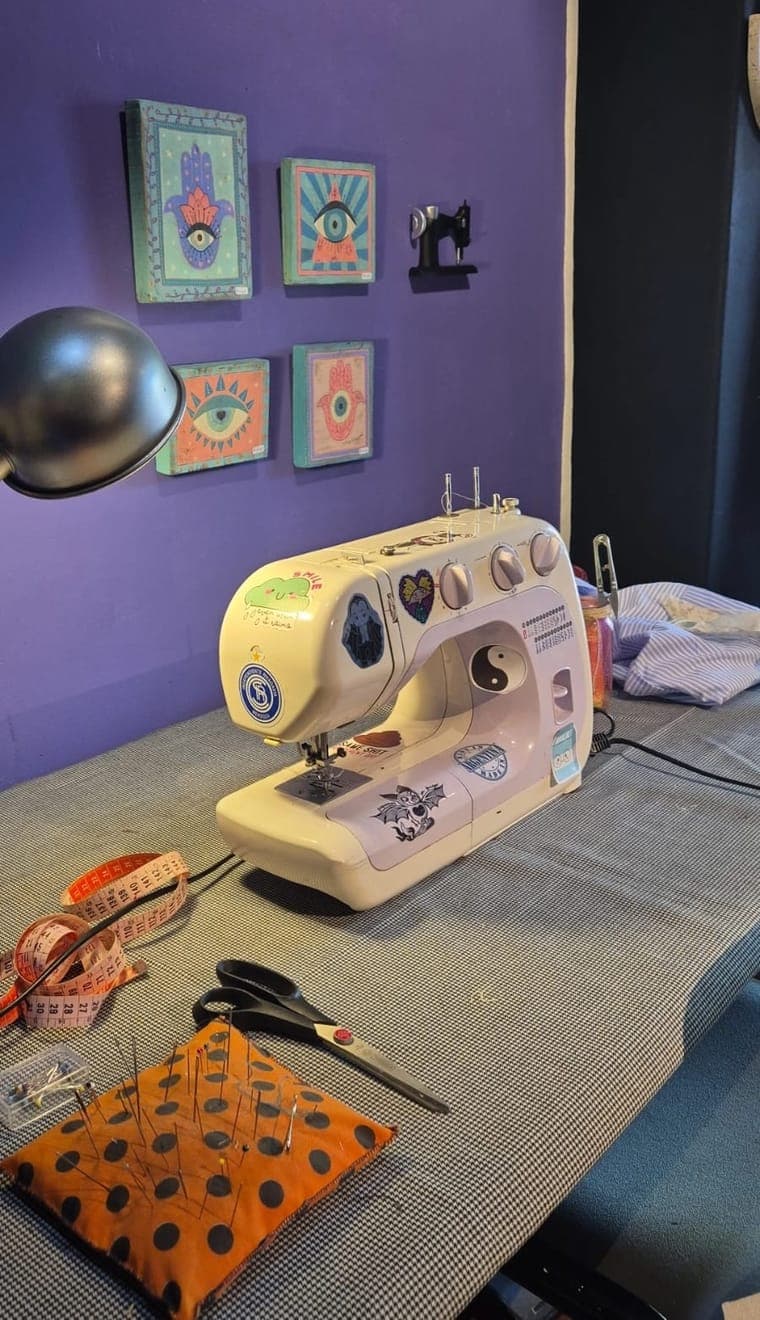 Máquina de coser en el taller de LAMATTA con arte de ojos y hamsas en la pared